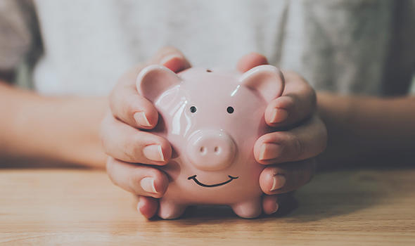 Freepik_man-hand-holding-piggy-bank-on-wood-table_monsterstudio_590x350.jpg